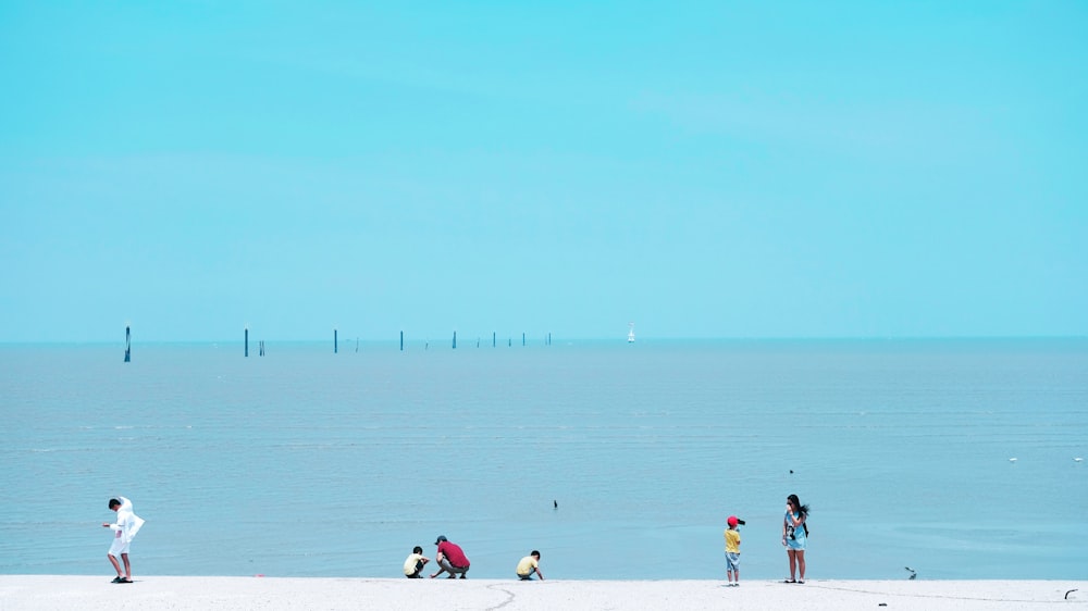 a group of people standing on top of a sandy beach