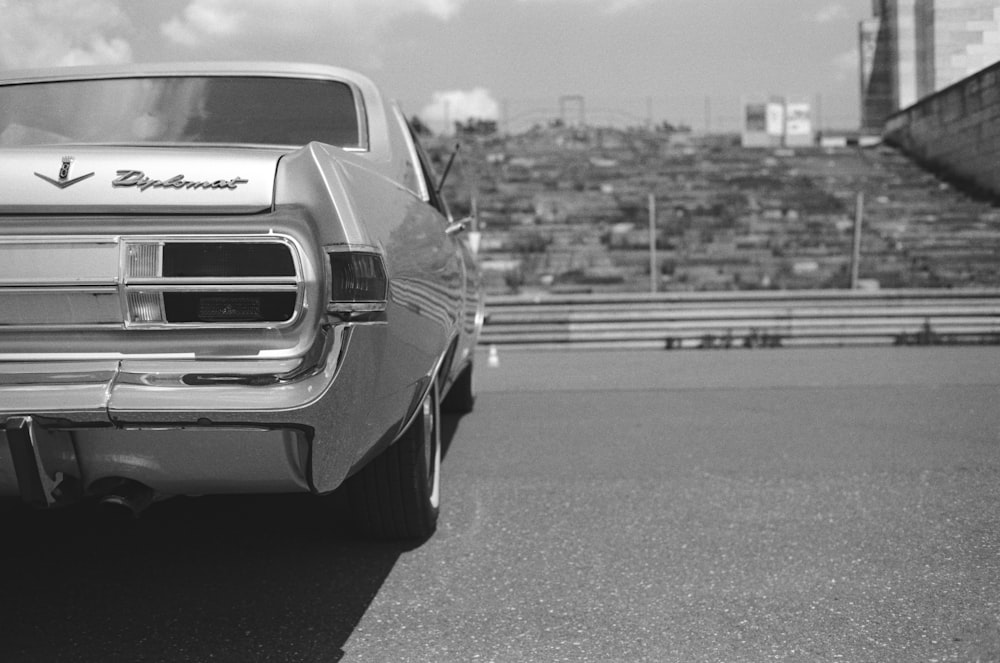 a black and white photo of a car parked on the side of a road