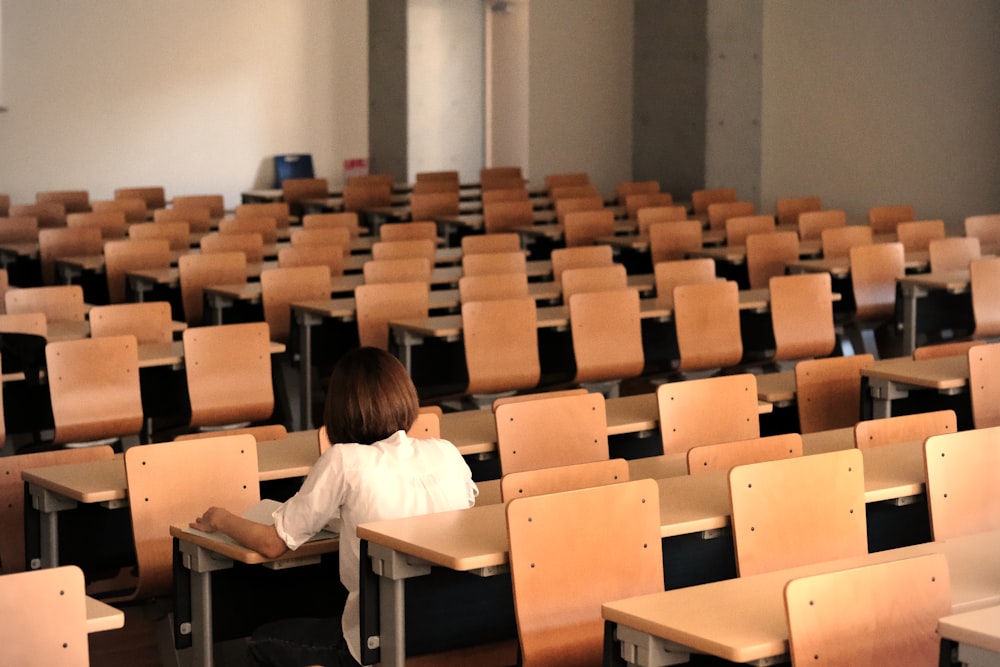 a young girl sitting in a classroom with a book