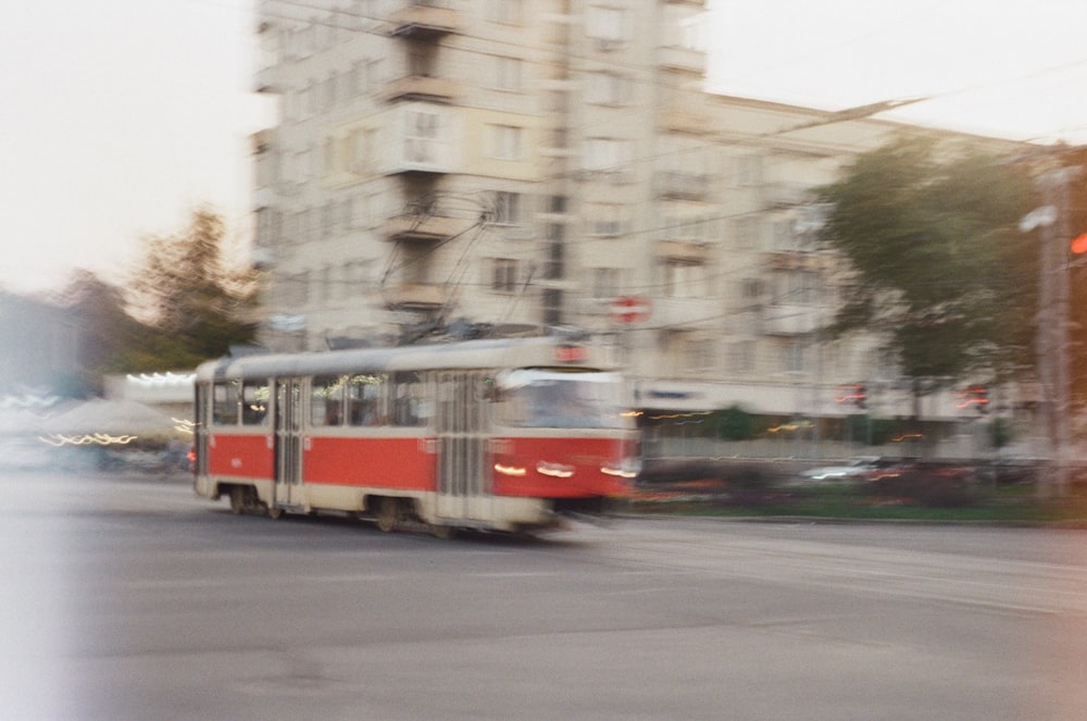 a red and white trolley driving down a street