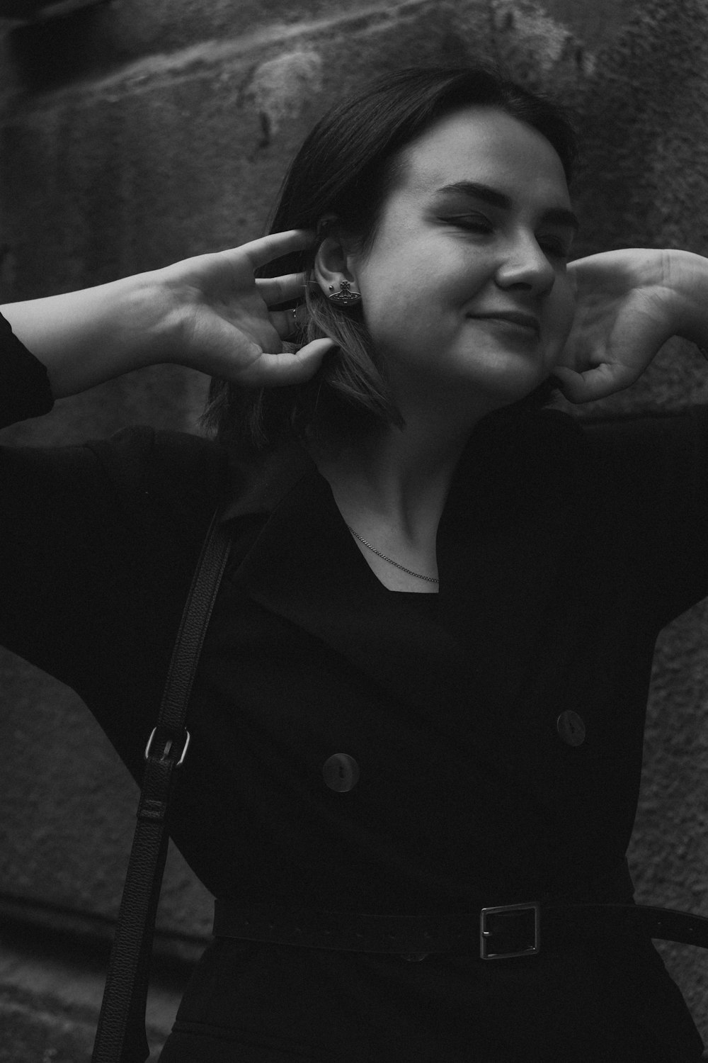 a black and white photo of a woman with her hands on her ears