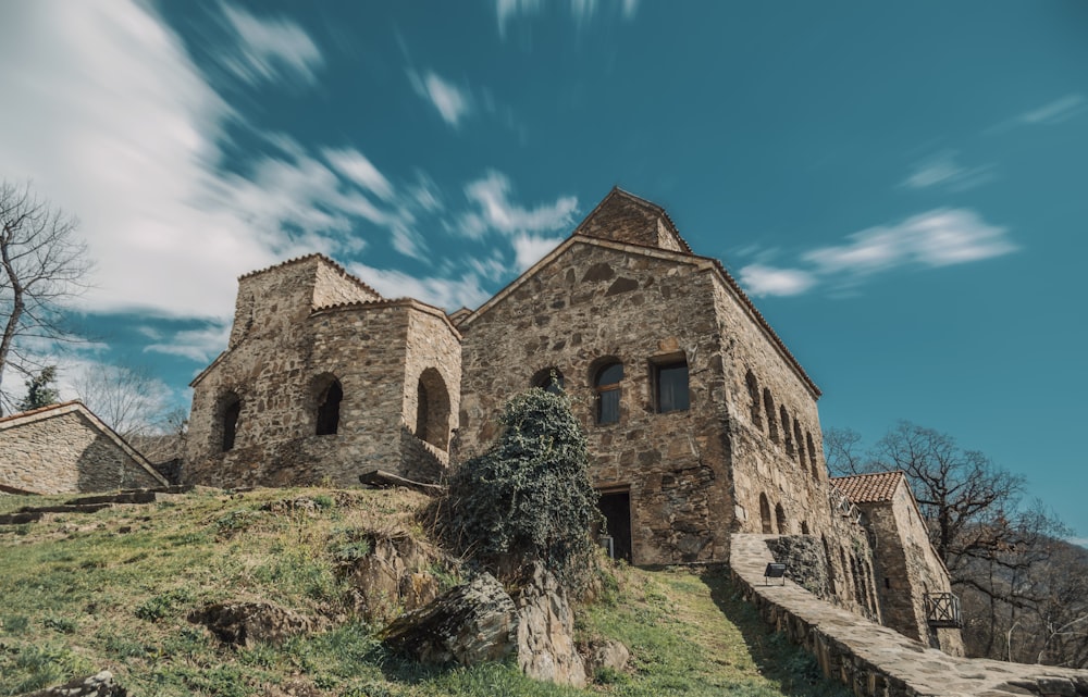 a large stone building sitting on top of a lush green hillside