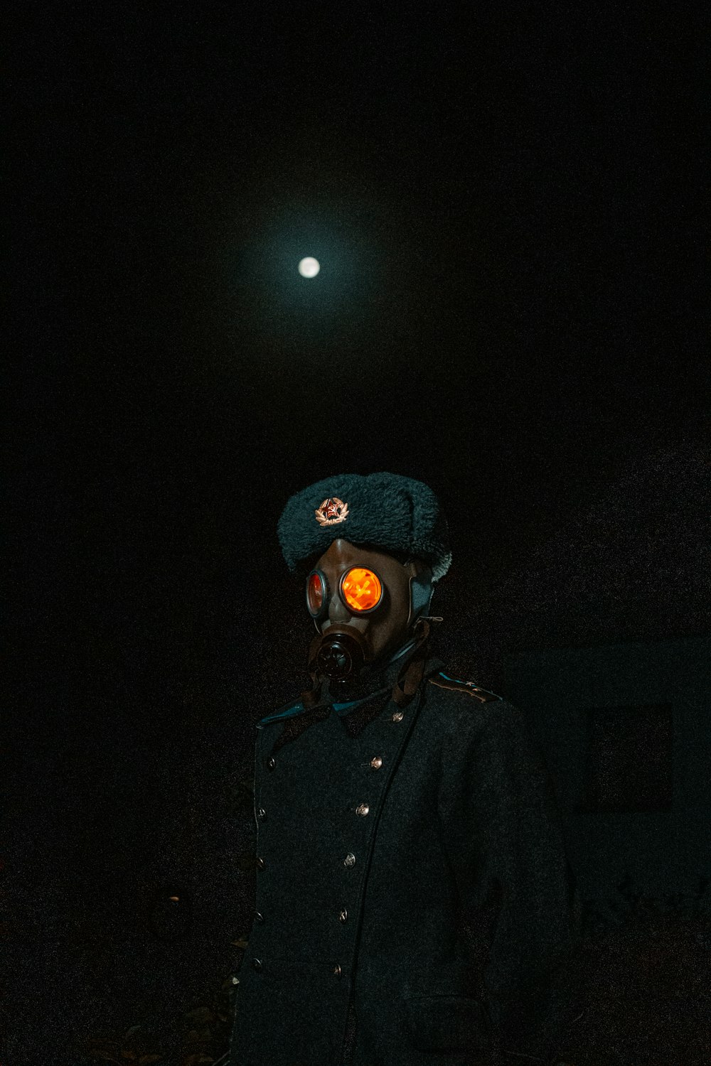 a man wearing a hat and a gas mask in the dark