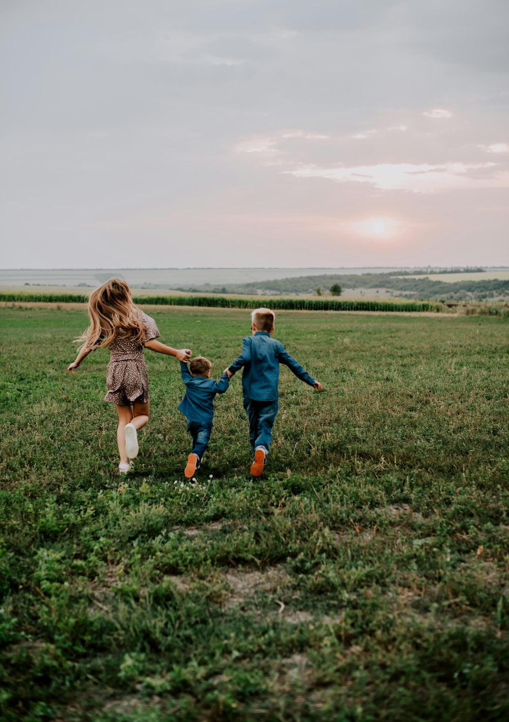 a couple of kids running across a lush green field