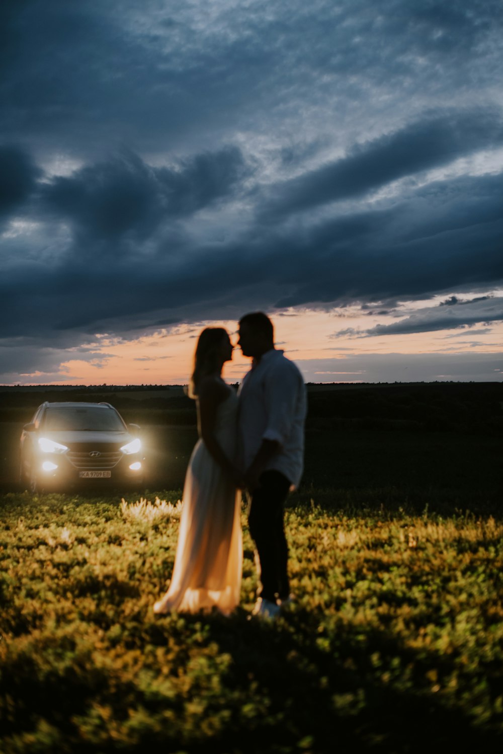 a bride and groom standing in front of a car