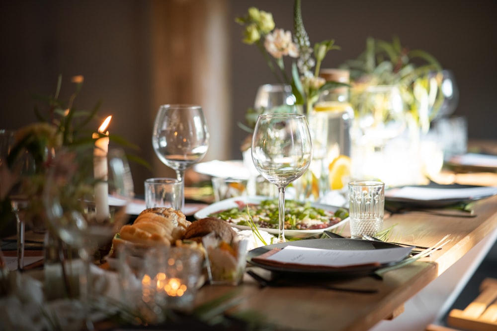 a table set for a formal dinner with wine glasses and plates