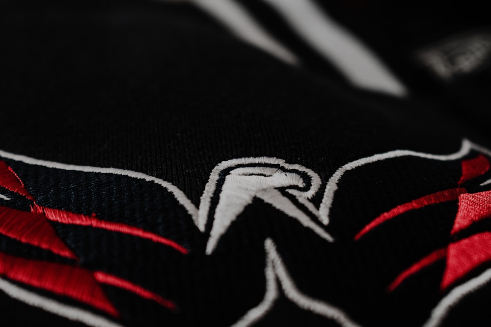 Un primer plano de una camiseta negra y roja con un águila