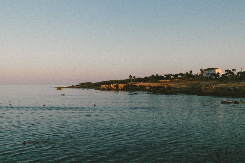 a body of water with a house on a hill in the background