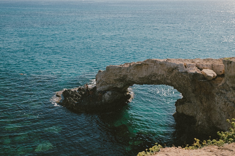 a rock arch in the middle of a body of water