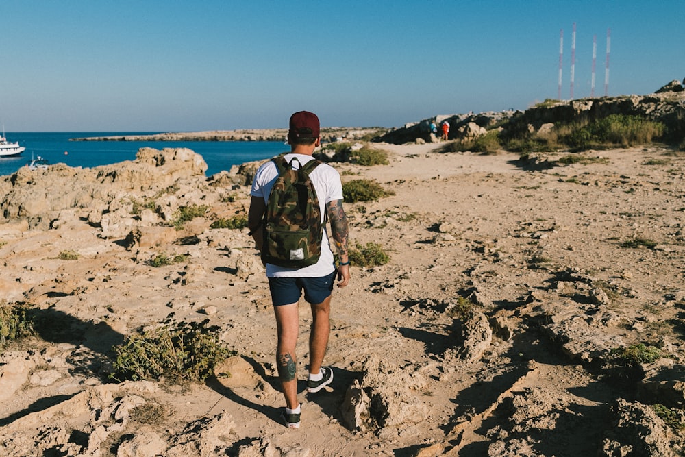 a man with a backpack walking on a rocky beach