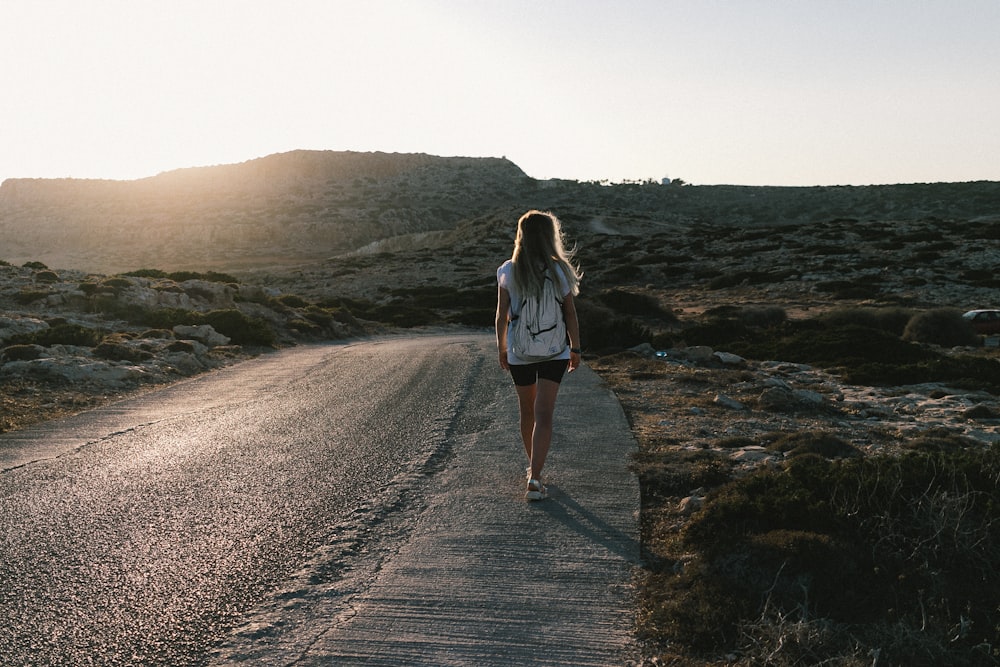 a woman walking down a road in the desert