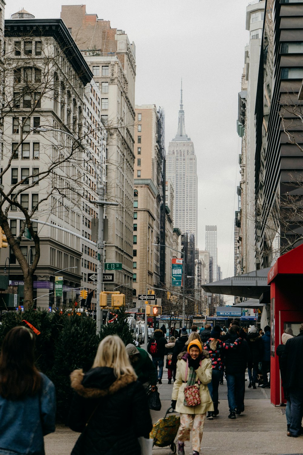 a group of people walking down a street next to tall buildings