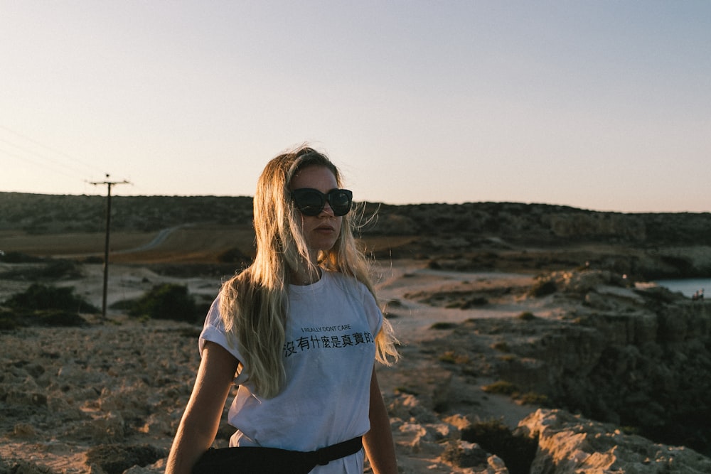 a woman wearing sunglasses standing in a desert