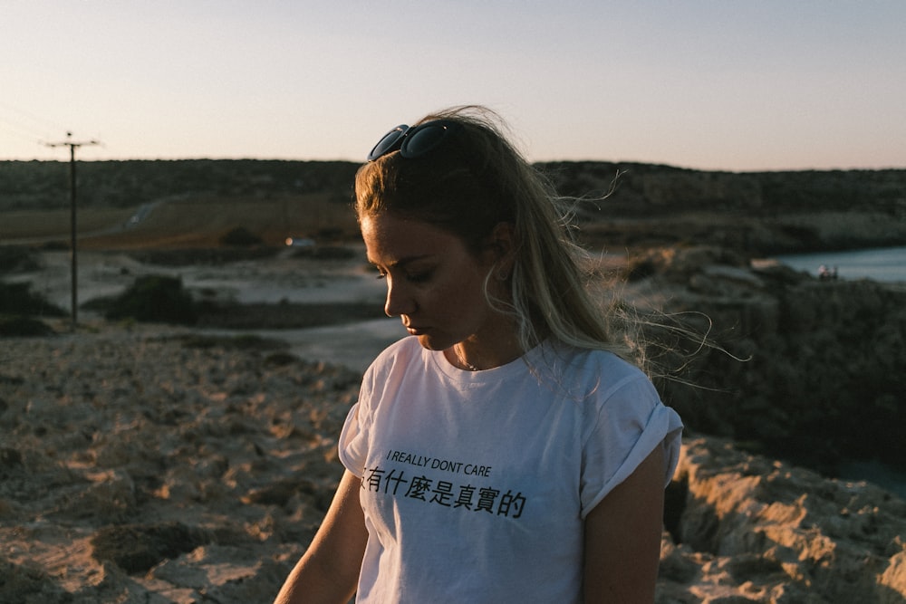 a woman in a white shirt is standing in the sand