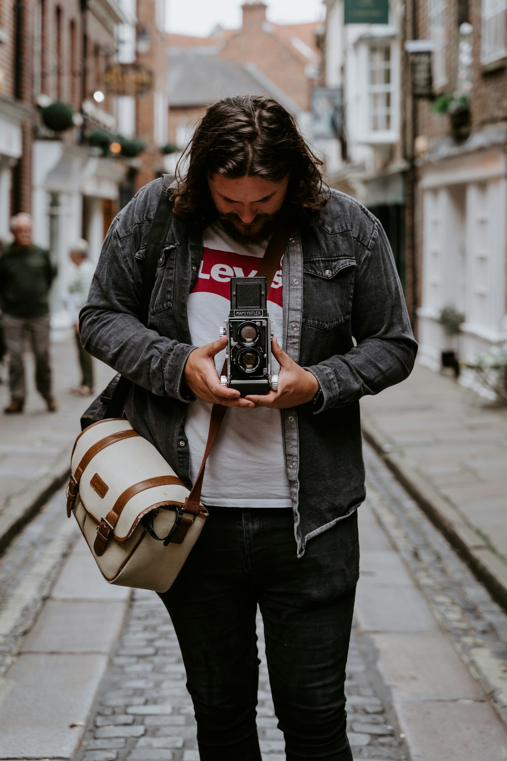 a man walking down a street holding a camera