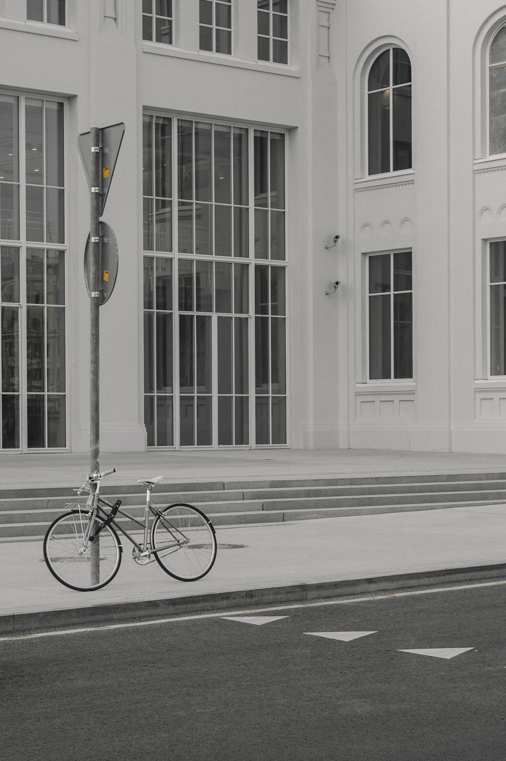 a black and white photo of a bike parked on the side of the road