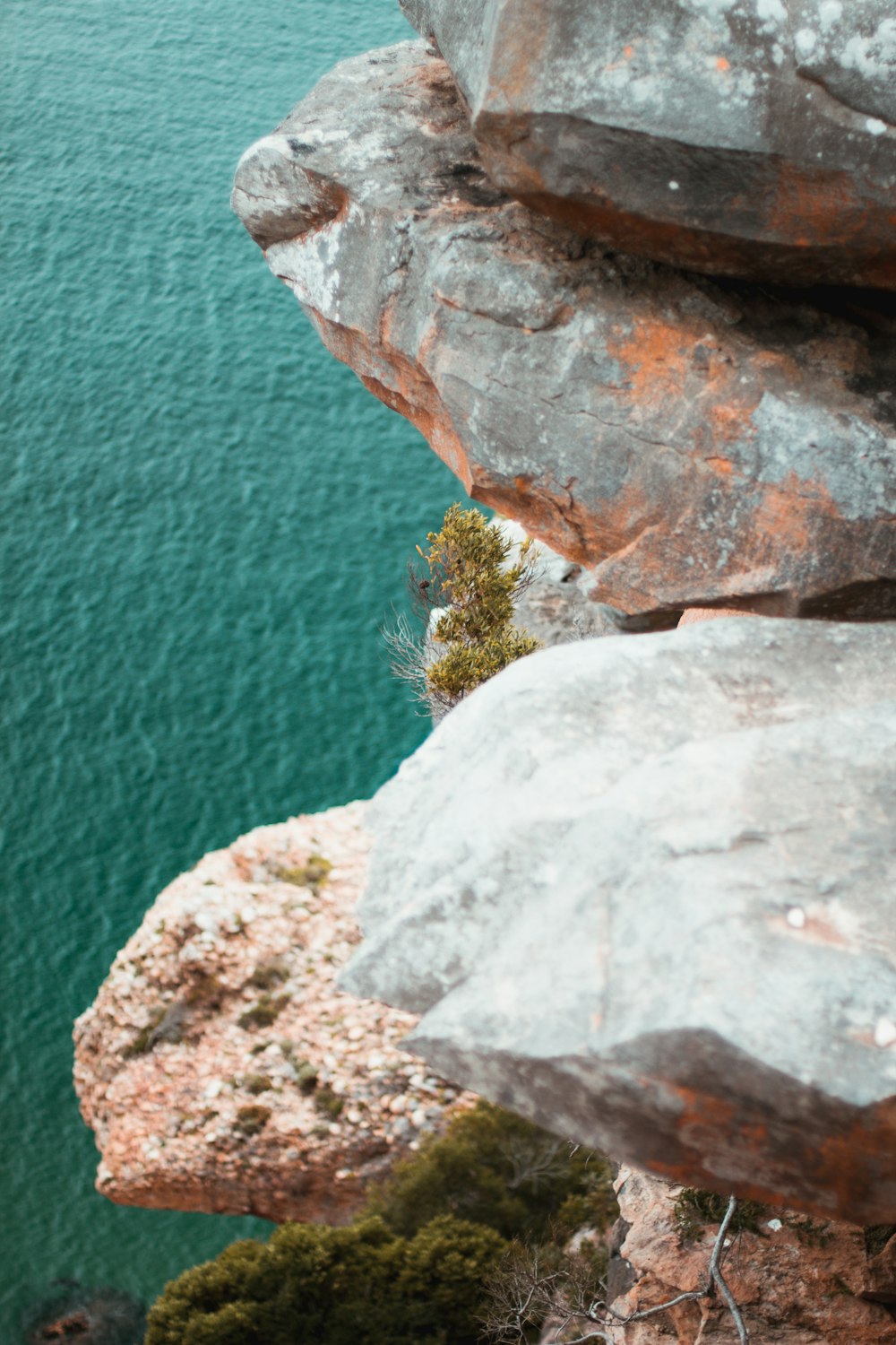 Una persona parada en la cima de un acantilado junto a un cuerpo de agua