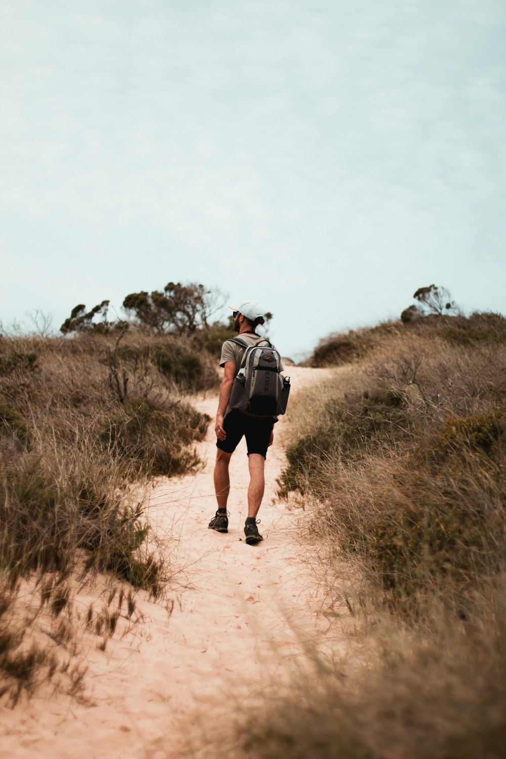 a man with a backpack walking up a dirt path