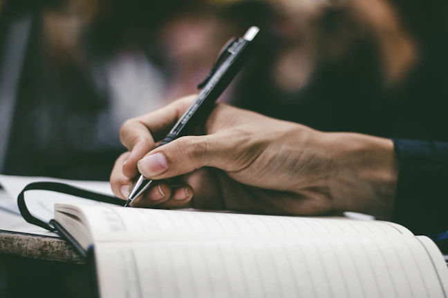Close-up of hands holding a notebook and pen during a therapy session