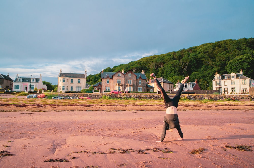 a person doing a handstand on a sandy beach