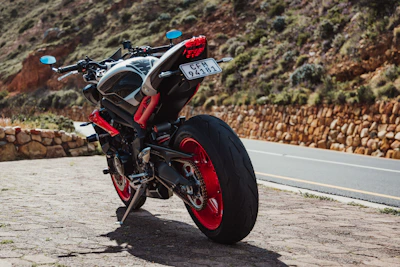 A shiny red sports motorcycle on an open road with mountains in the background