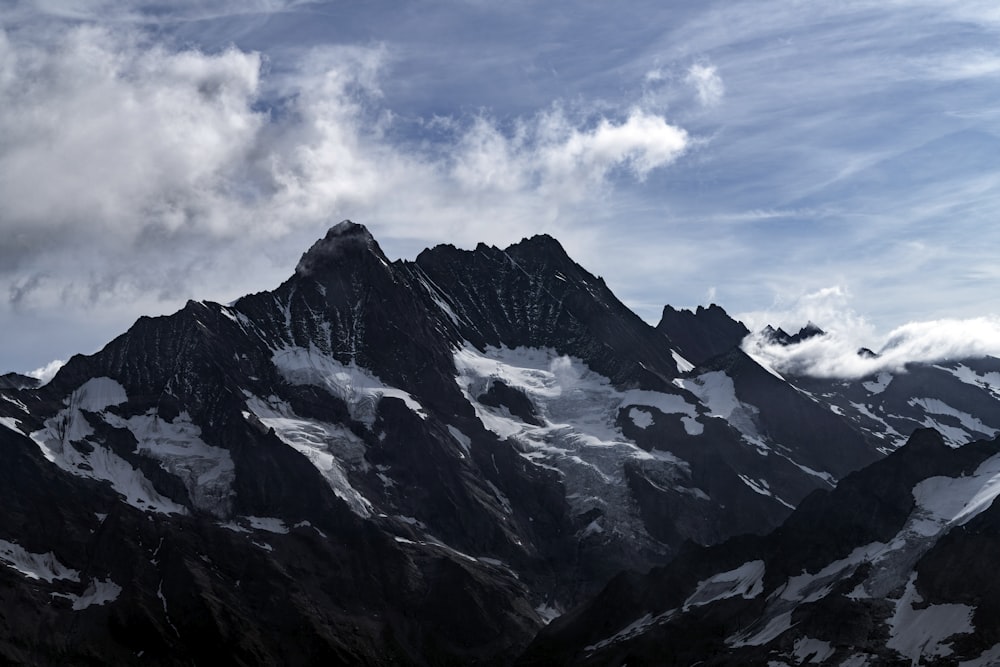 a very tall mountain covered in snow under a cloudy sky