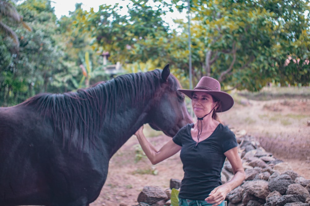 a woman standing next to a black horse