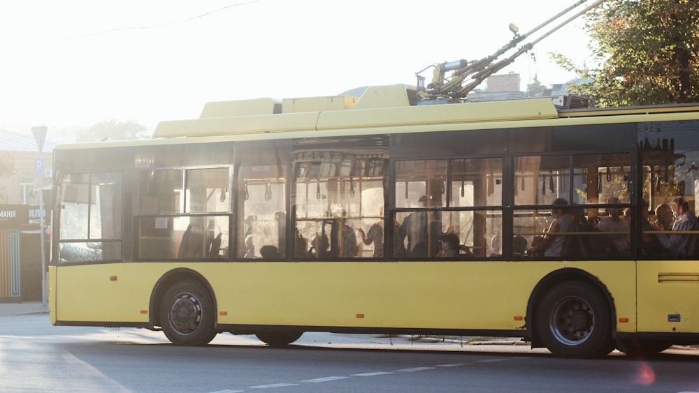 a yellow bus driving down a street next to a tall building