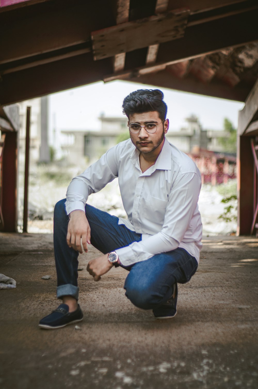 a man in a white shirt and jeans crouching down