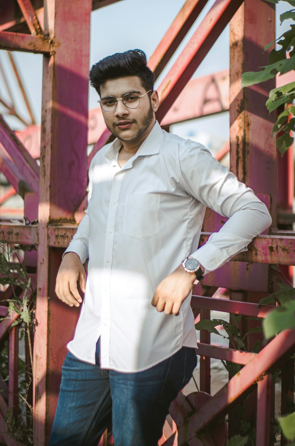 a man in a white shirt leaning against a metal structure