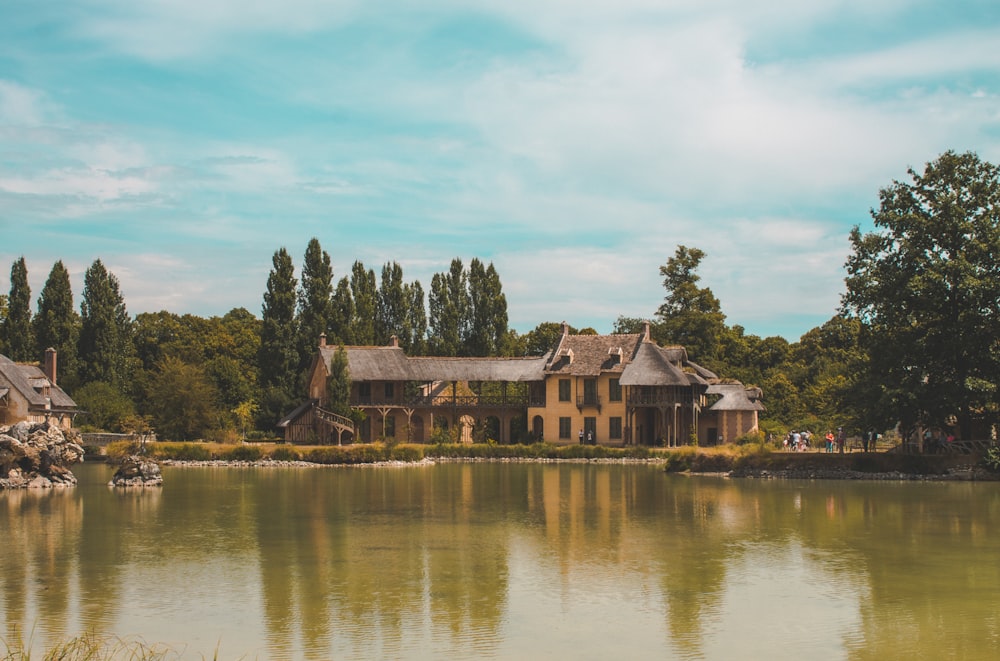 Una gran casa sentada en la cima de un lago junto a un bosque