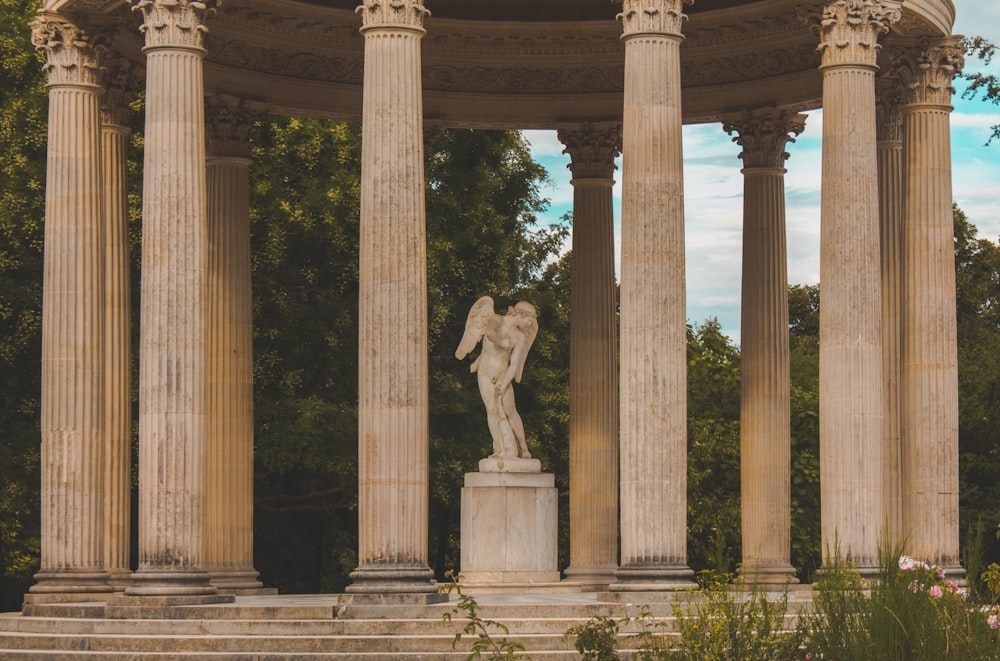 une statue d’ange sur un piédestal entouré de piliers