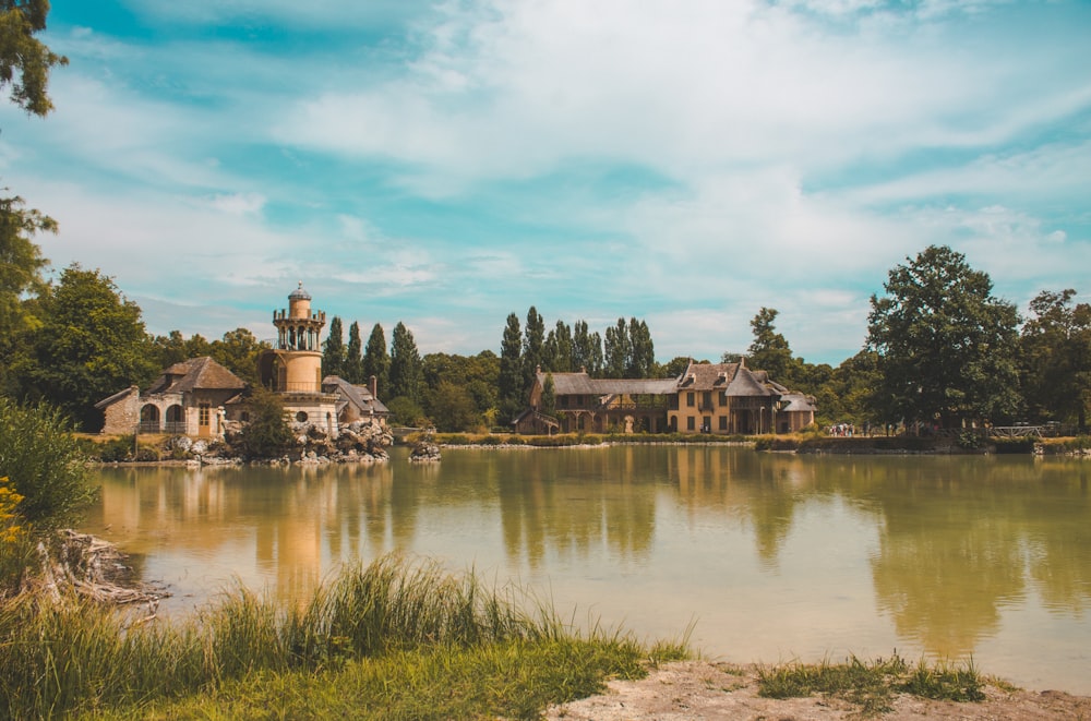 a lake surrounded by trees with a building in the background