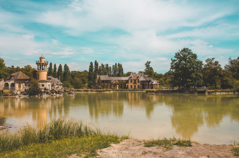 a lake surrounded by trees with a building in the background