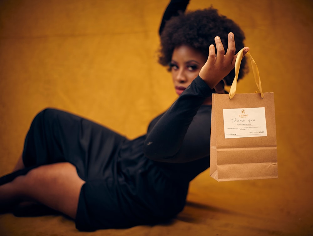a woman sitting on the floor holding a brown bag