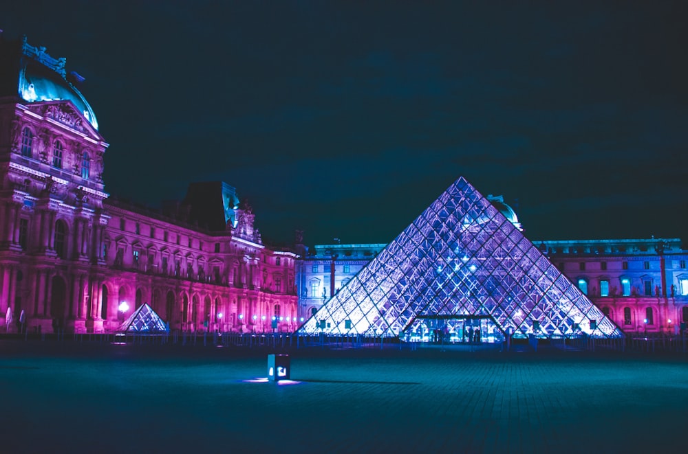 a large building with a glass pyramid in front of it