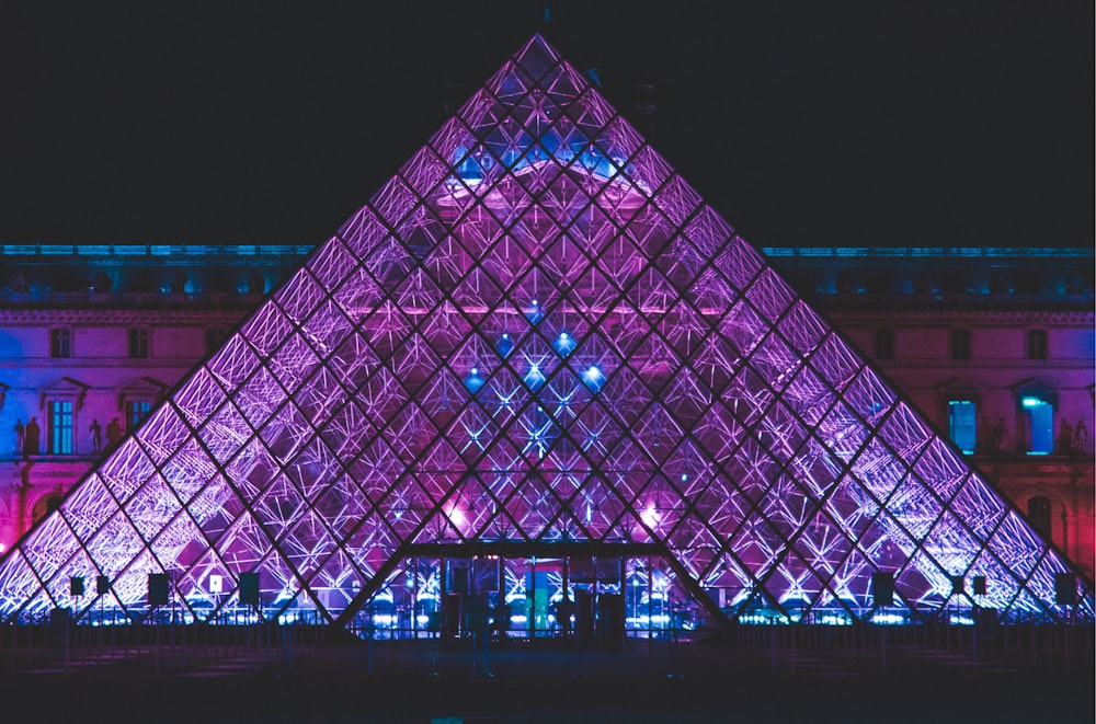 um grande edifício em forma de pirâmide iluminado à noite