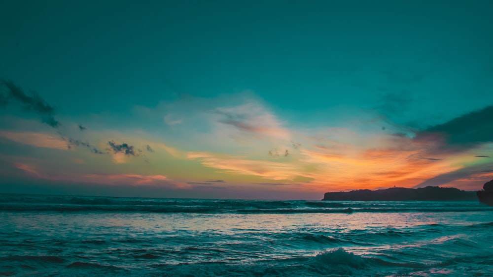 a beautiful sunset over the ocean with waves