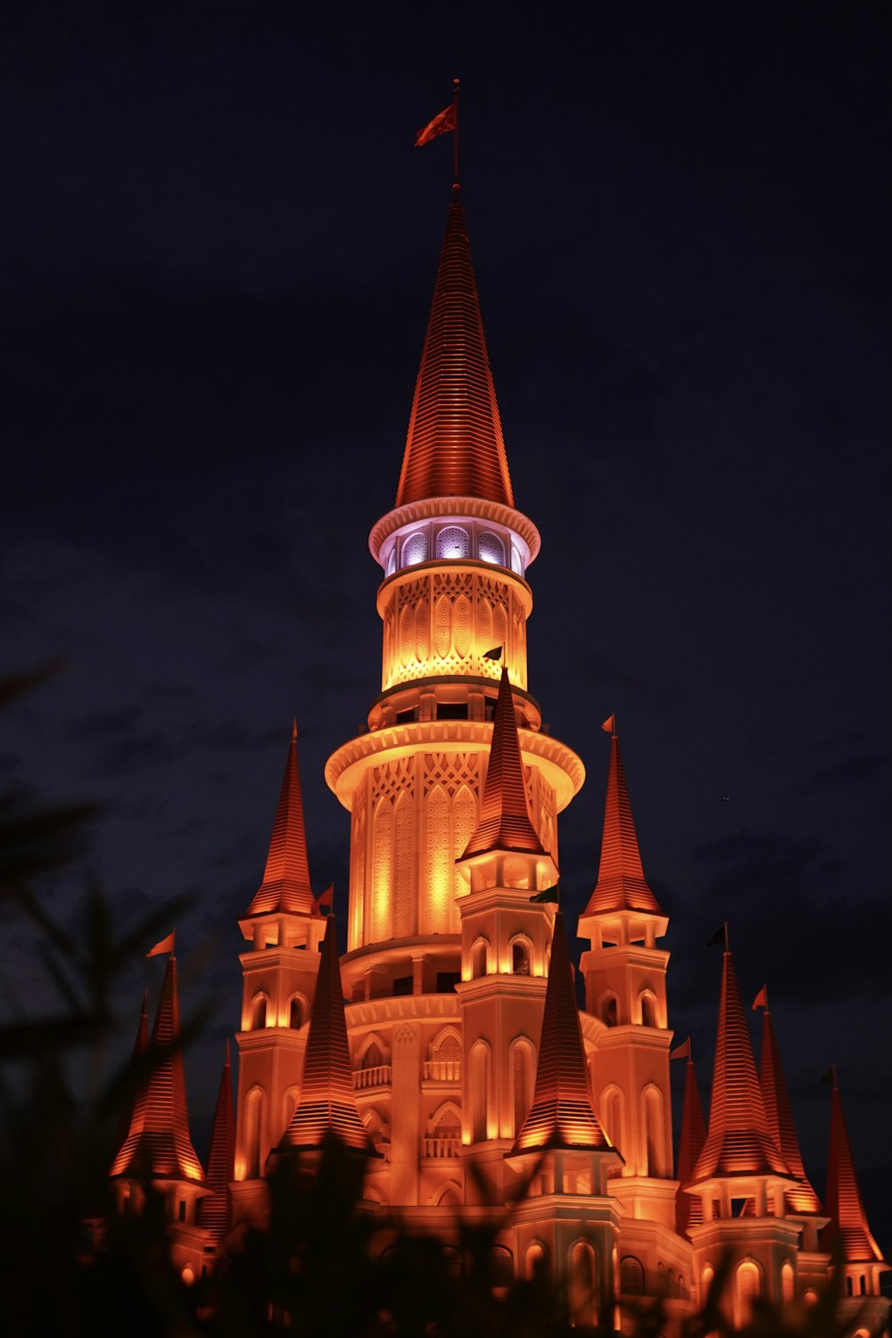 Un castillo iluminado por la noche con una bandera en la parte superior