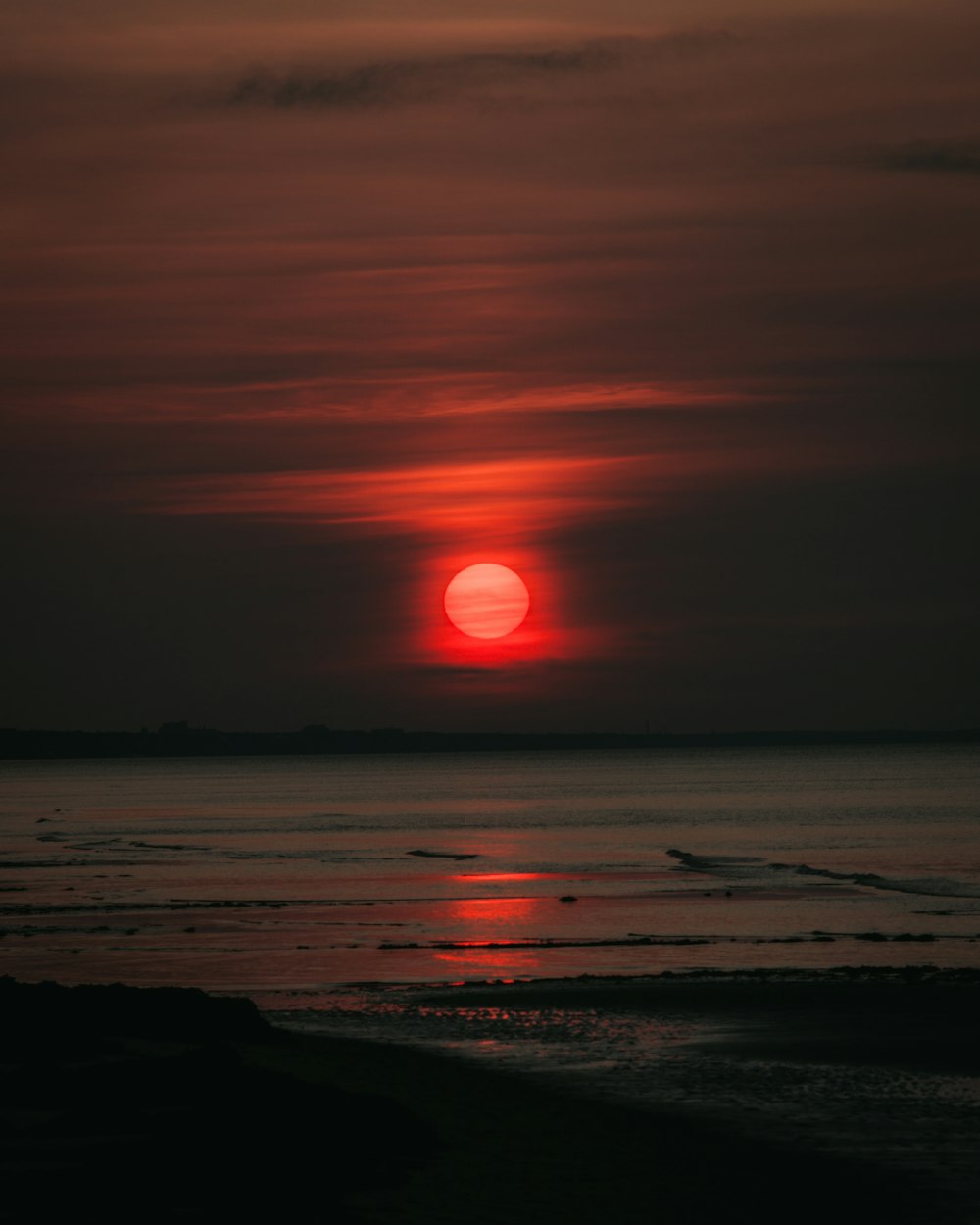 the sun is setting over the ocean on a cloudy day