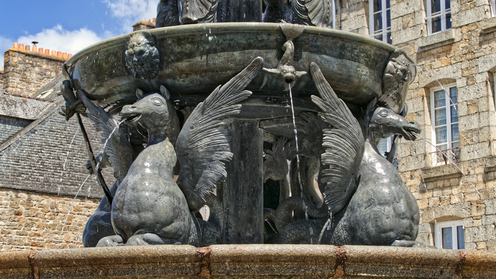 a fountain with statues of birds on it in front of a building