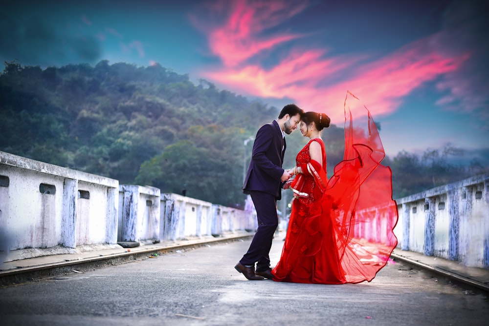 Un hombre y una mujer con vestido rojo parados uno al lado del otro