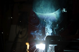 welder working on a piece of metal in the dark