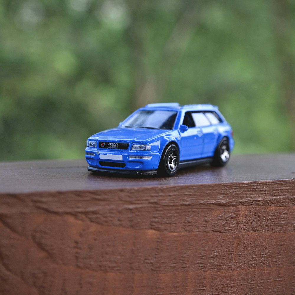a blue toy car sitting on top of a wooden table