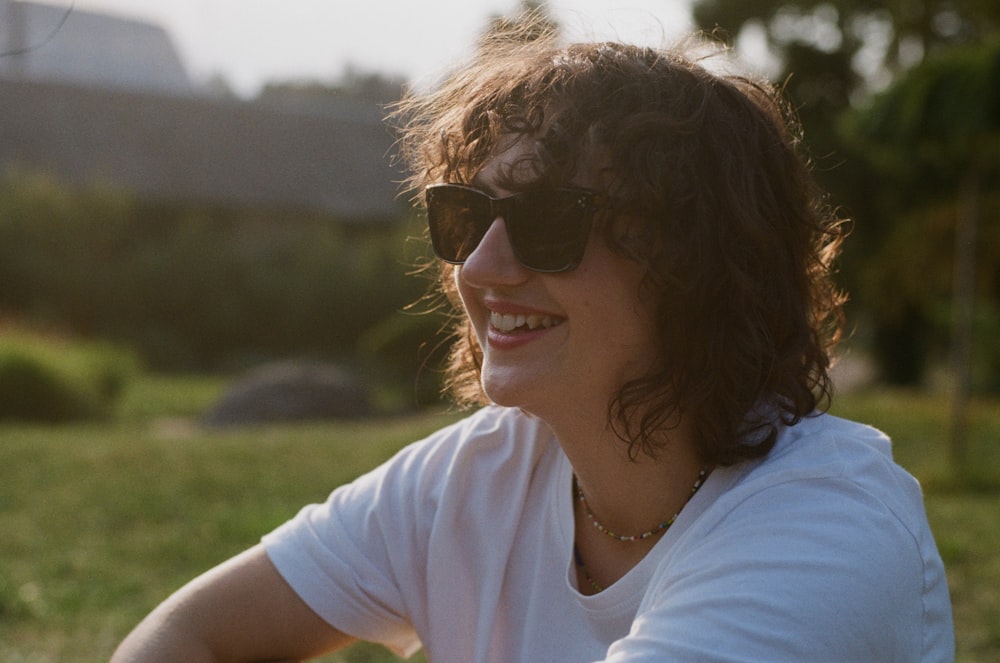 a woman wearing sunglasses sitting in a field