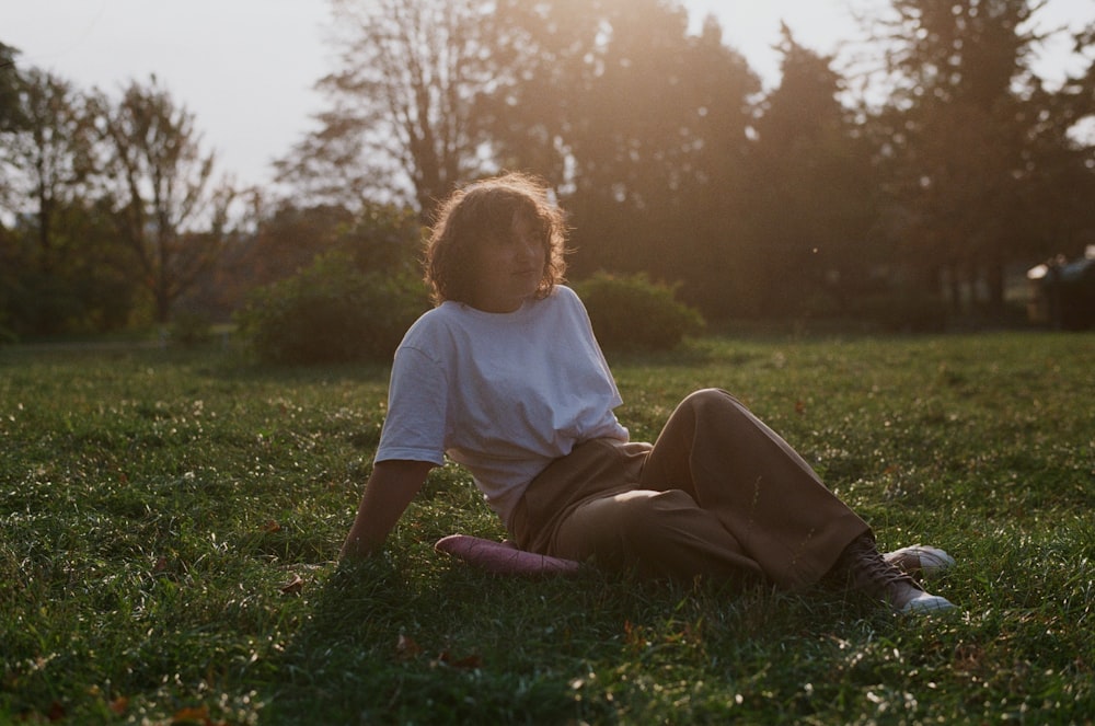 a young boy sitting on top of a grass covered field