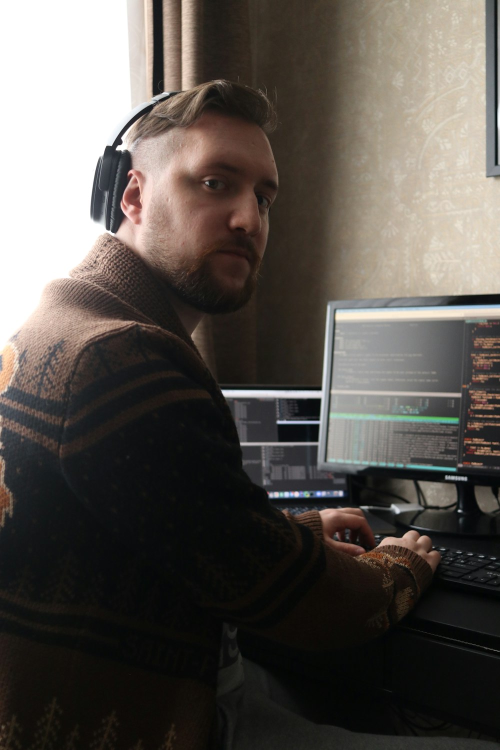 a man sitting at a computer with headphones on