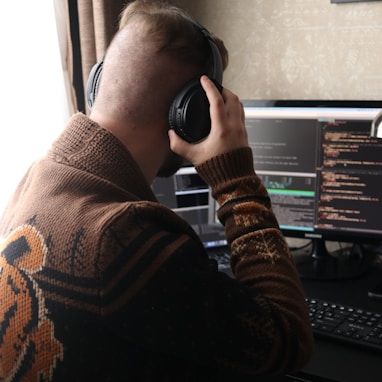 a man sitting in front of a computer with headphones on