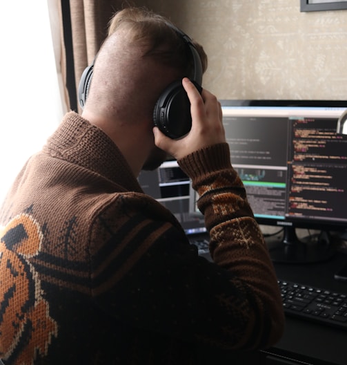 a man sitting in front of a computer with headphones on