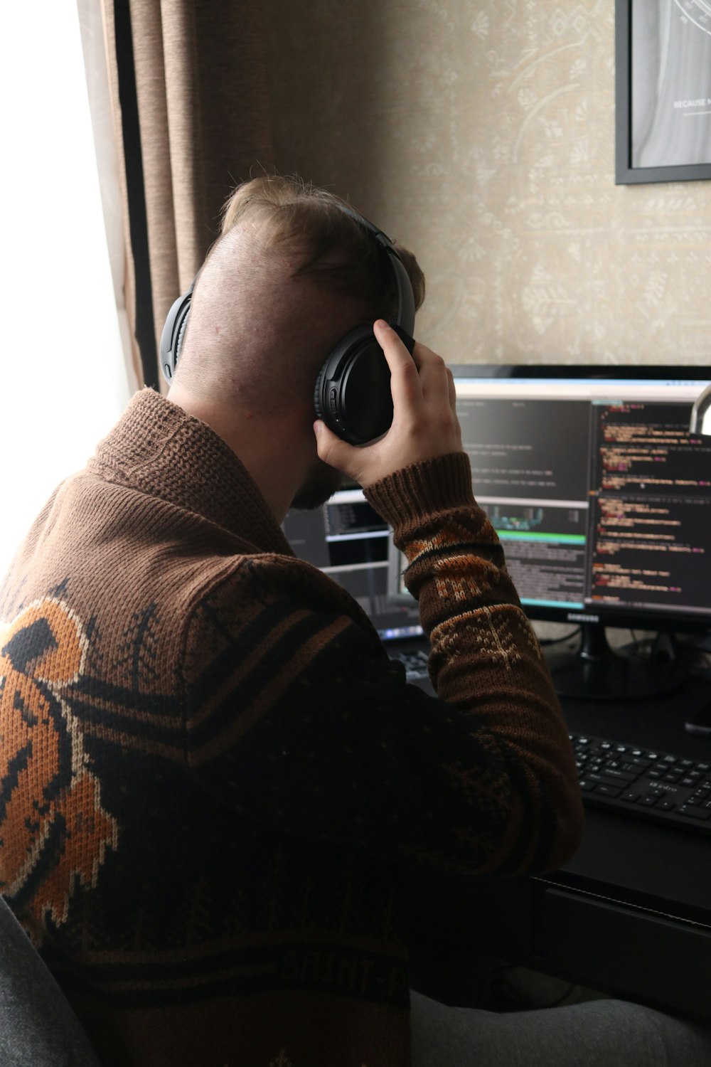 ヘッドフォンをつけたままコンピューターの前に座っている男性